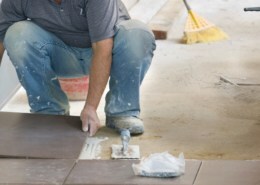 man laying tiles on natural stone tile adhesive