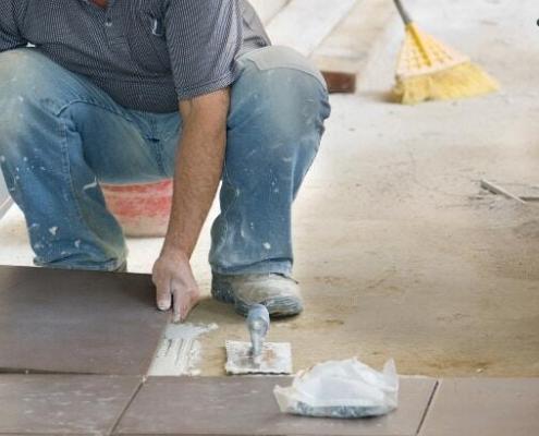 man laying tiles on natural stone tile adhesive