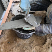 man applyin masonry veneer mortar at the back of a tile